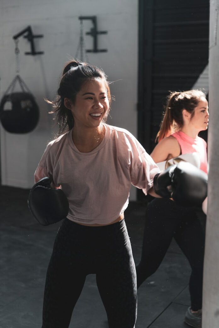 Photo by LOGAN WEAVER | @LGNWVR woman in pink long sleeve shirt and black pants holding black kettle bell
