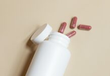 유산균의 효능과 섭취 방법 a white bottle with red and white pills