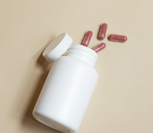 유산균의 효능과 섭취 방법 a white bottle with red and white pills