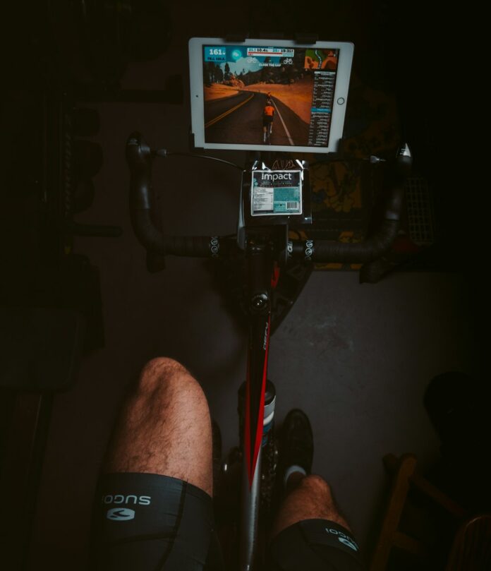 Photo by Algi person in black shorts sitting on black and red stationary bike