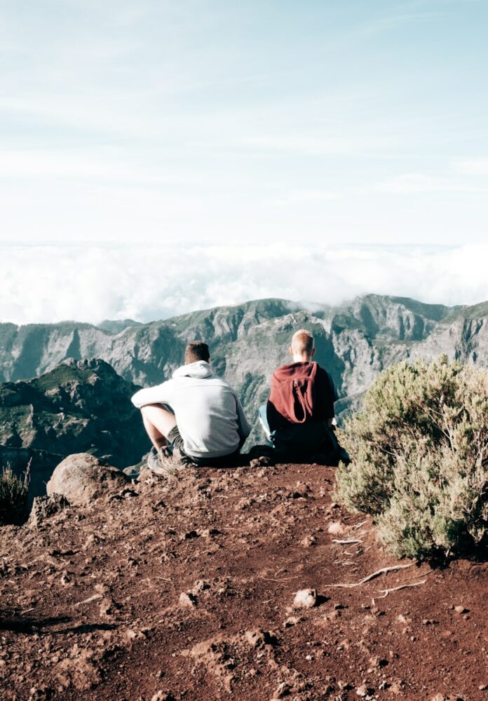 Photo by Daniele Franchi a couple of people sitting on top of a mountain