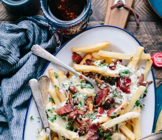 운동 전후로 먹으면 좋은 음식과 피해야 할 음식 bacon strips and melted cheese topped fries on oval white and blue platter with gray stainless steel forks
