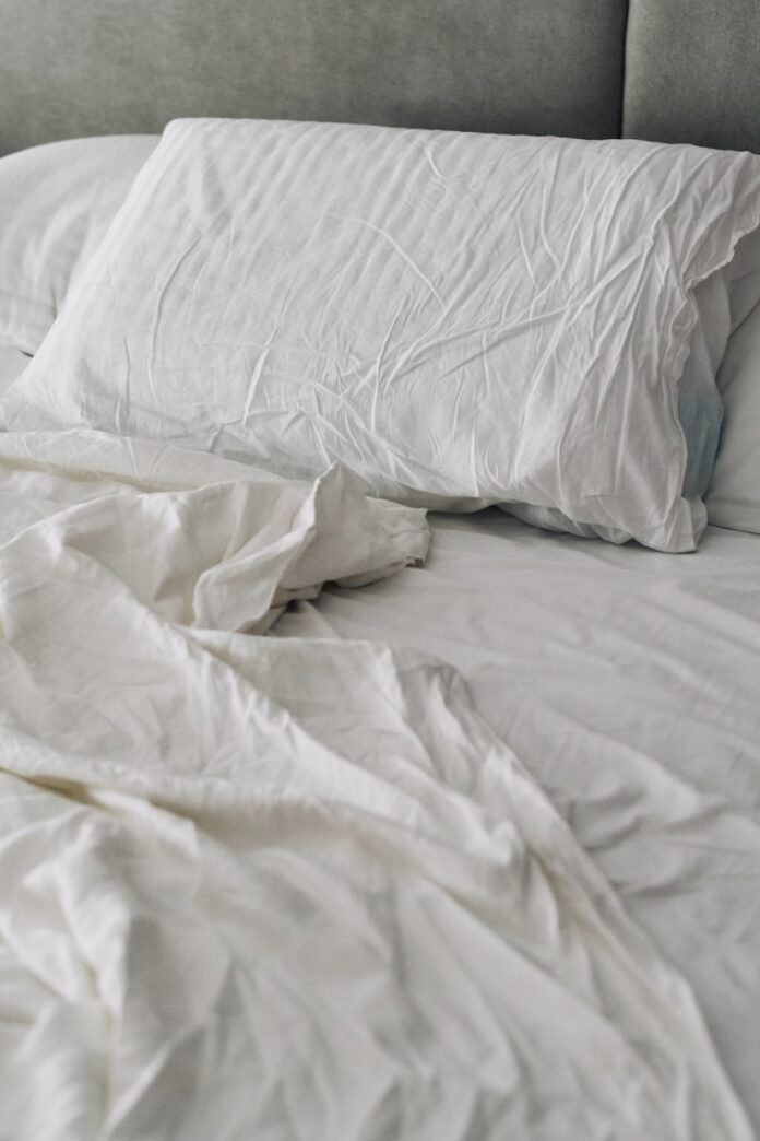 Photo by Dina Makhmutova A rumpled white duvet and pillows on a bed.