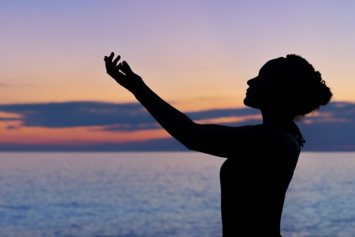 Photo by William Farlow silhouette of woman raising her right hand
