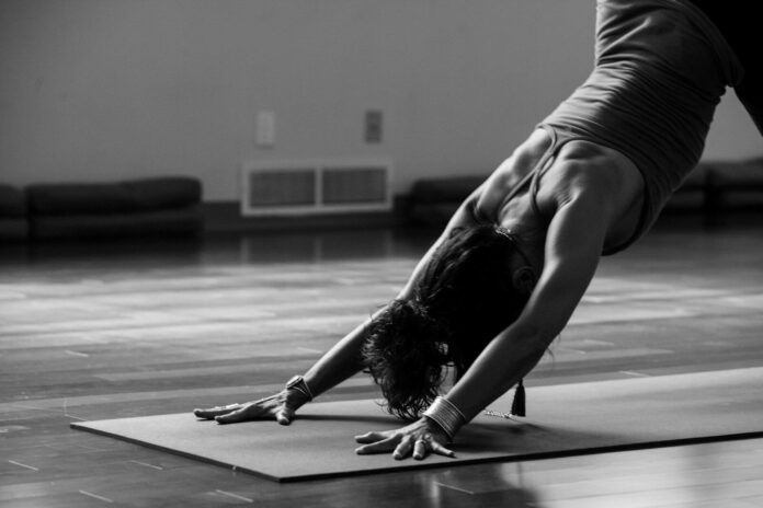 Photo by Ginny Rose Stewart woman in black tank top and black pants bending her body on floor